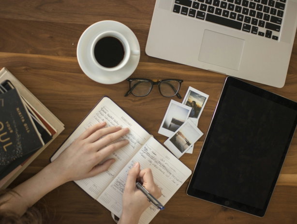 person holding ballpoint pen writing on notebook